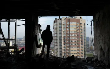 Silhouette einer Person in einem zerstörten Gebäude, die auf ein Wohnhaus in der Ukraine blickt, Illustration des Anstiegs der zivilen Opfer im Juli 2026 laut UN