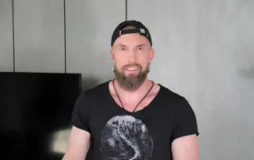 Алексей Суровцев в черной футболке и кепке, демонстрирующий уверенность и успех в своей карьере в 2026 году