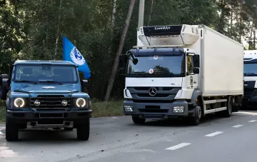 Вантажівка з червоним хрестом та військовий джип на дорозі, що символізують процес репатріації тіл загиблих українських військовослужбовців
