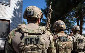 SBU-Beamte in Tarnuniformen mit Emblemen auf Helmen und Rucksäcken, die an einer Operation zur Zerstörung des GRU-Netzwerks teilnehmen, das Angriffe auf ukrainische Luftwaffenbasen vorbereitete.