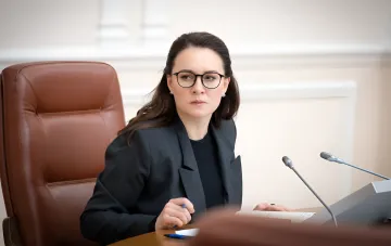 Оксана Свириденко в офисе: серьезный взгляд за столом с документами, символизирующий её роль в «Нафтогазе» и политические риски назначения