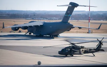Бойовий вертоліт Apache на аеродромі поруч із транспортним літаком C-17 — ілюстрація до новини про катастрофу в Техасі
