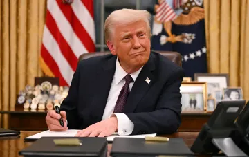Дональд Трамп за столом в Овальном кабинете подписывает указ о введении высоких пошлин на импорт дронов