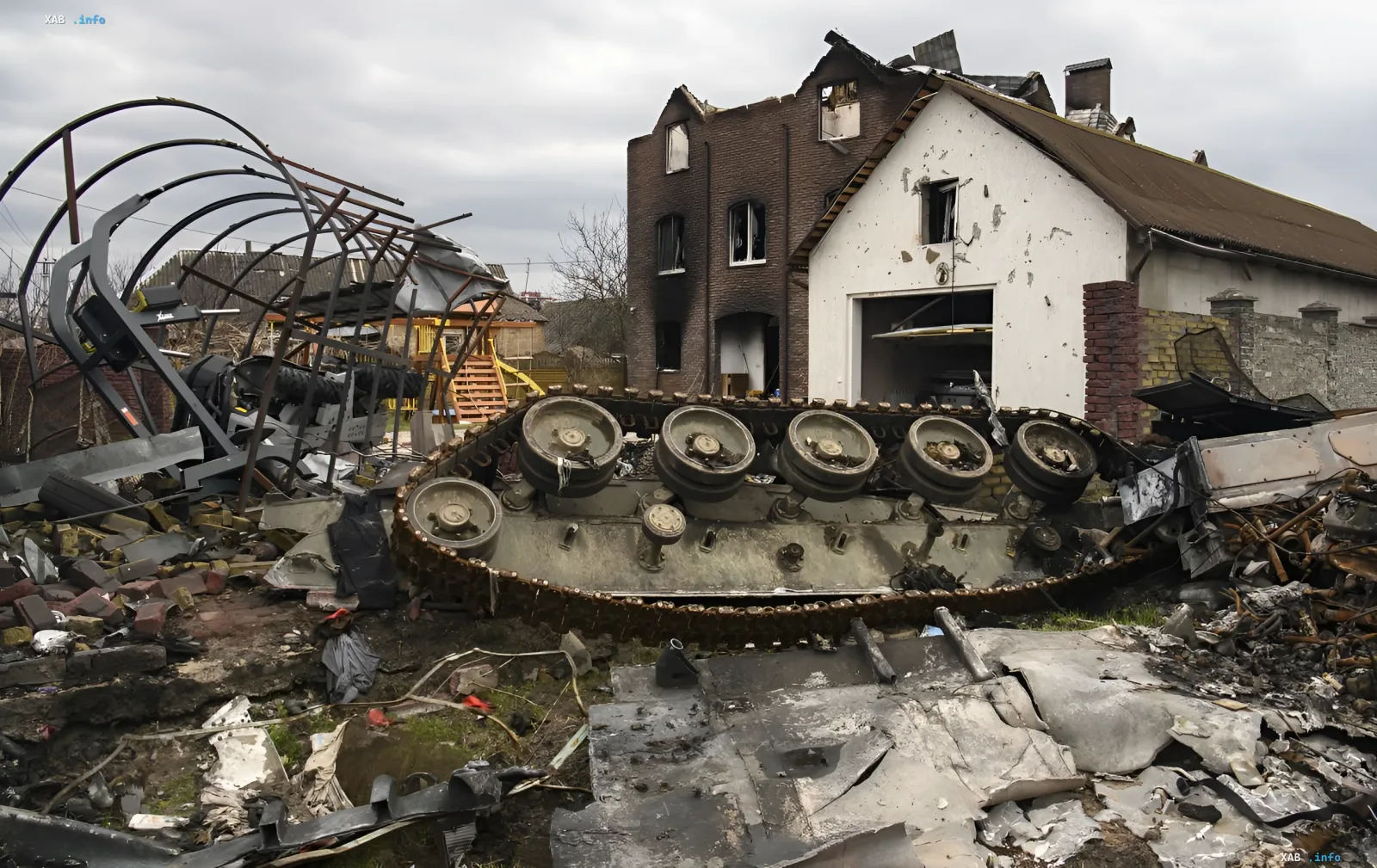 Zerstörte russische Panzerkette und Trümmer von Militärfahrzeugen vor einem beschädigten Haus