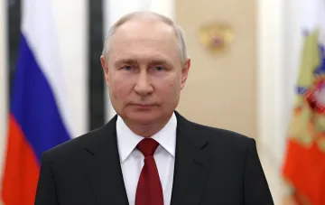Владимир Путин в официальном костюме на фоне российского флага, связанный с визитом на Итуруп и территориальным спором с Японией