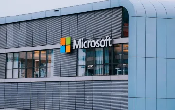 Логотип Microsoft на фасаде современного здания, иллюстрирующий тему августовского Patch Tuesday 2026 и закрытия уязвимостей