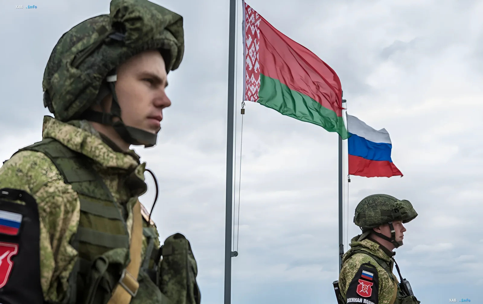 Belarussische Soldaten im Tarnanzug vor den Flaggen von Belarus und Russland — Symbol verstärkter militärischer Präsenz an der Grenze