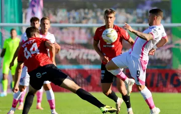 Player from Epitsentr in red-black kit tries to win the ball from Veres defender in white with pink accents during UPL match in Dunayivtsi