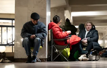 Eine Gruppe älterer Menschen sitzt auf Klappstühlen in einem öffentlichen Gebäude und wartet auf Wärme während der Winterheizungsabschaltungen in Kiew