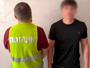 Полицейский в жилете с надписью «ПОЛІЦІЯ» допрашивает подозреваемого — 20-летнего одессита, обманувшего экс-нардепа на $32 000 под видом проверки СБУ