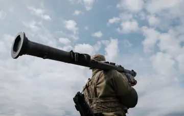 Украинский военнослужащий с переносной зенитно-ракетной установкой на фоне неба, готовый к отражению атаки дронов
