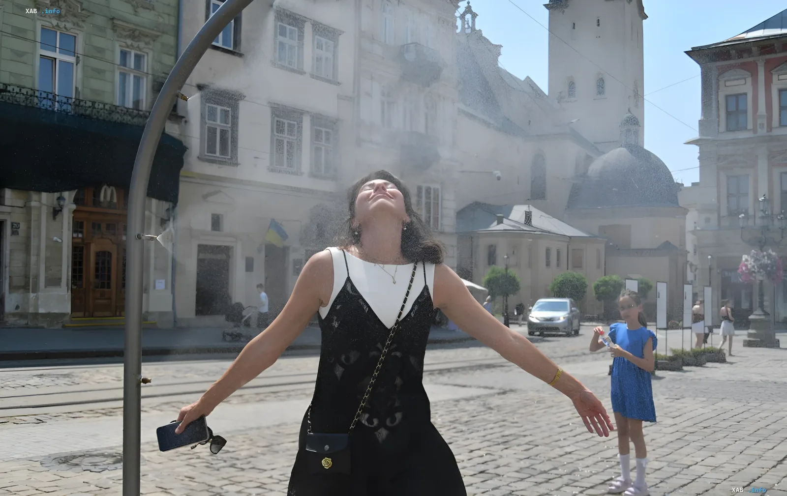 Woman enjoying cool mist from a street fountain in a Ukrainian city, symbolizing relief from the +33°C August 2026 heatwave