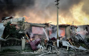 Firefighters extinguish a burning residential house in Sumy region after drone strikes, where a mother and child died