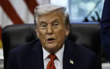 Дональд Трамп в костюме с американским флагом на лацкане, сидящий в кресле — кадр из спецоперации в Анкаре, где он тайно сбежал из аэропорта на грузовике кейтеринга из-за угрозы Ирана