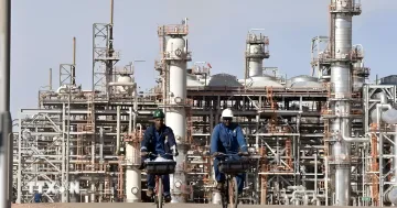 Работники на велосипедах перед газоперерабатывающим заводом в Алжире, символизирующие рост поставок газа в Испанию
