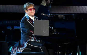 Элтон Джон в ярком костюме играет на пианино Yamaha, демонстрируя свой уникальный стиль