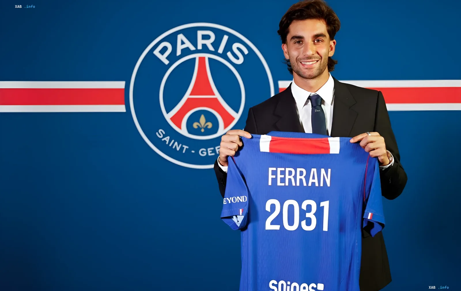 Ферран Торрес у костюмі тримає футболку ПСЖ з ім'ям FERRAN та датою 2031 на фоні логотипу клубу