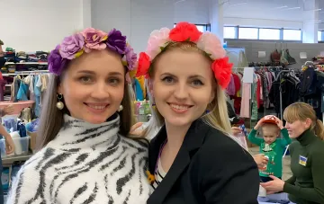 Ukrainische Frauen in Blumenkränzen lächeln vor humanitärer Hilfe und symbolisieren echte EU-Unterstützung, die von russischer Propaganda im Kontext von „Reserve+' verzerrt wird