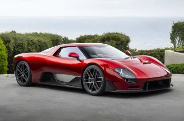 Красный McLaren McLaren 6GT на фоне побережья, демонстрирующий классический дизайн и механическую коробку передач