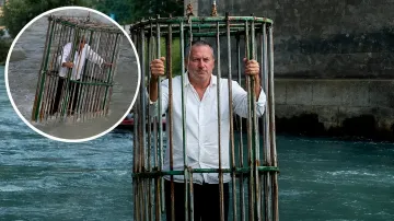 Politiker in weißem Hemd steht in einem Metallkäfig, der in einen Fluss in Trient getaucht ist, als Teil einer symbolischen Bestrafung für schlechte Arbeit