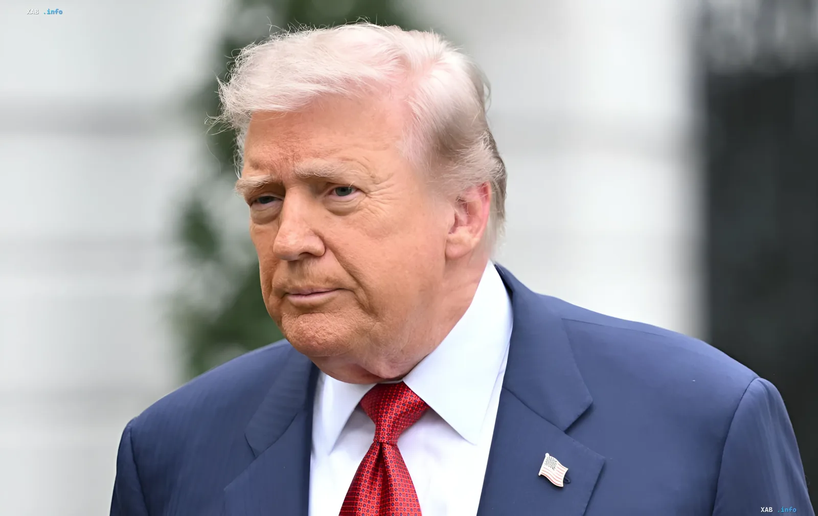 Donald Trump in einem blauen Anzug mit einer amerikanischen Flagge am Revers, was die Spannung in den Beziehungen zu den US-Verbündeten im Persischen Golf symbolisiert