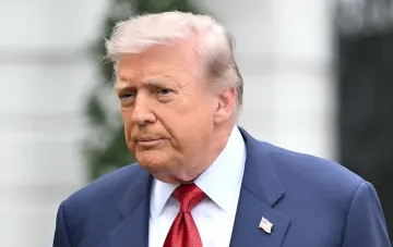 Дональд Трамп в синем костюме с американским флагом на лацкане, символизирующий напряженность в отношениях с союзниками США в Персидском заливе