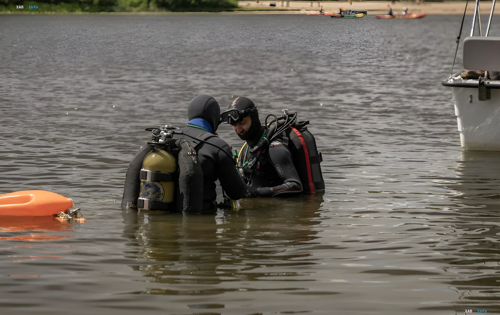 Rettungskräfte in Neoprenanzügen und Tauchausrüstung arbeiten im Wasser, wahrscheinlich bei Suchaktionen nach dem Verschwinden eines Teenagers