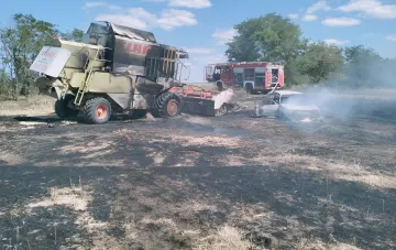 Сгоревший зерноуборочный комбайн Claas и автомобиль после удара дрона в Запорожском районе, пожарные на месте происшествия