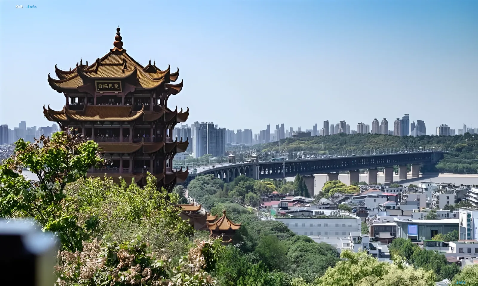 Panoramic view of Wuhan: ancient pagoda in foreground, Yangtze River bridge and modern skyline in background — symbolizing the city’s transformation from industrial hub to green oasis