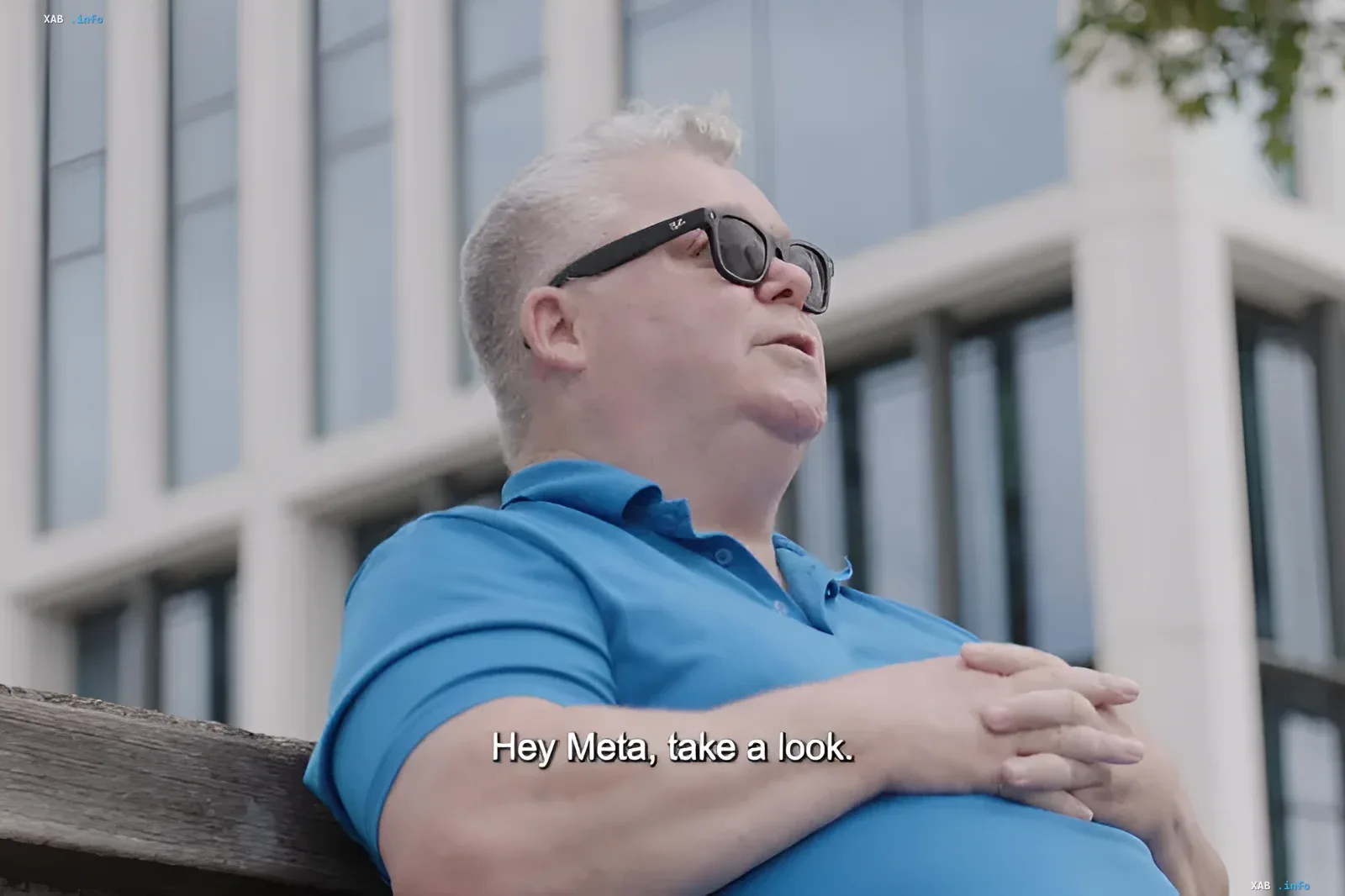 Мужчина в синей рубашке и умных очках Ray-Ban Meta сидит на скамейке, демонстрируя использование очков для слабовидящих