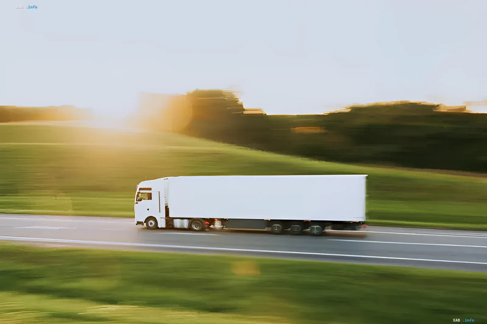 A truck with a white trailer drives along a highway against a sunset backdrop, symbolizing the transportation of AI servers intercepted by organized groups in the USA.