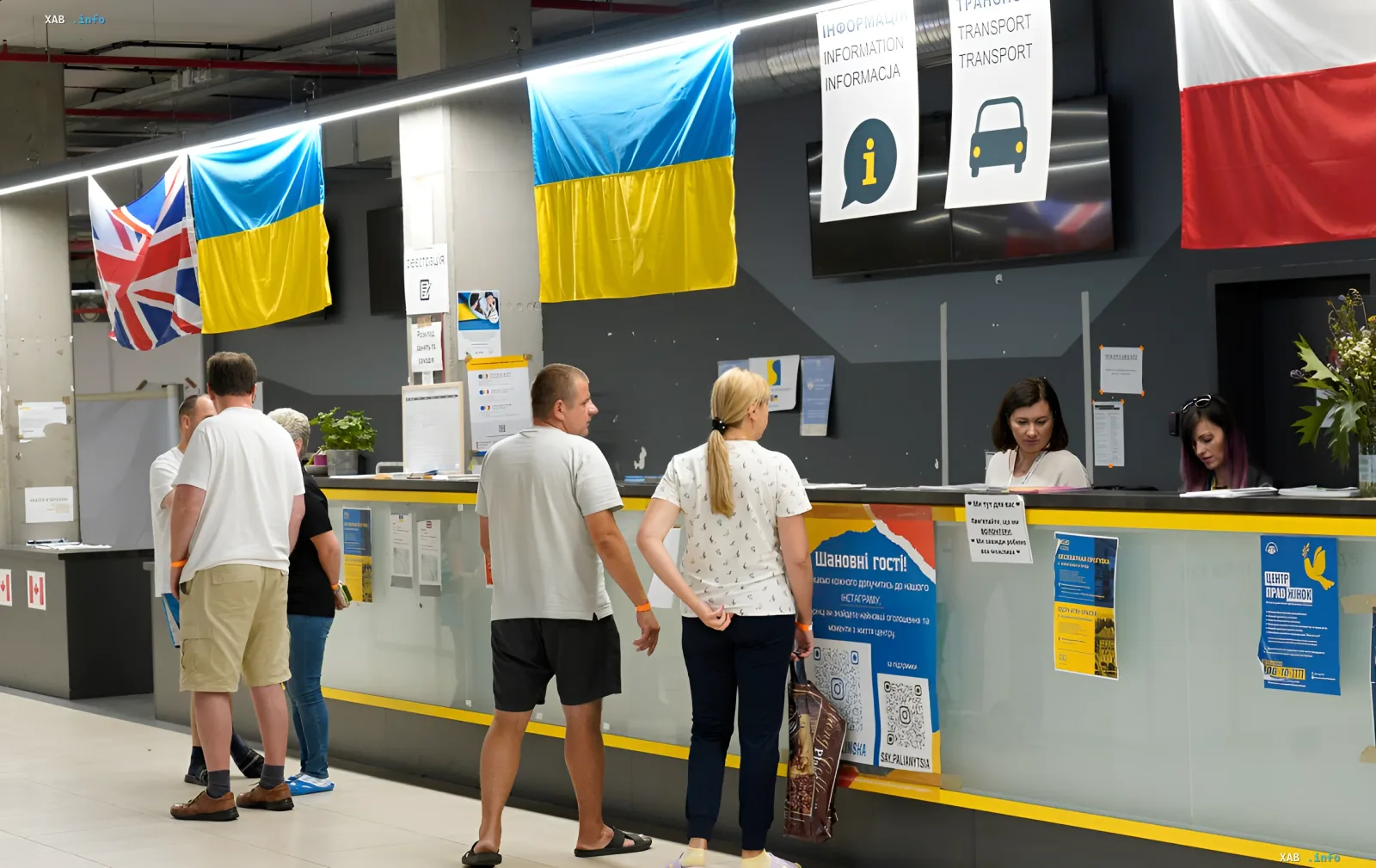 Украинцы в очереди в польском информационном центре на фоне флагов Украины и Польши