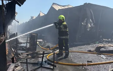 Rettungskraft löscht Brand am verbrannten Buchmarkt Potschajna in Kiew nach Raketenangriff