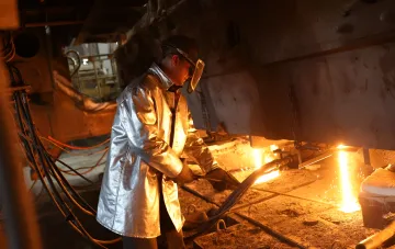 Рабочий в защитном костюме управляет потоком расплавленного металла на заводе «АрселорМиттал Кривой Рог» перед ракетным ударом, приведшим к остановке производства