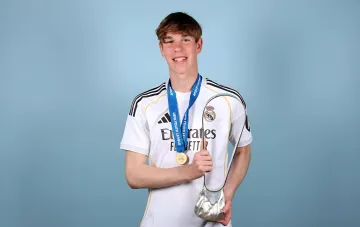 Иван Волошин в форме «Реала Мадрид» с медалью UEFA Youth League и трофеем, символизирующим его успехи в молодежном составе перед дебютом за основную команду