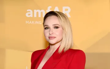 Хайден Панеттьери в красном пиджаке на фоне желтой стены с надписью amfAR, последняя улыбка перед трагическим финалом