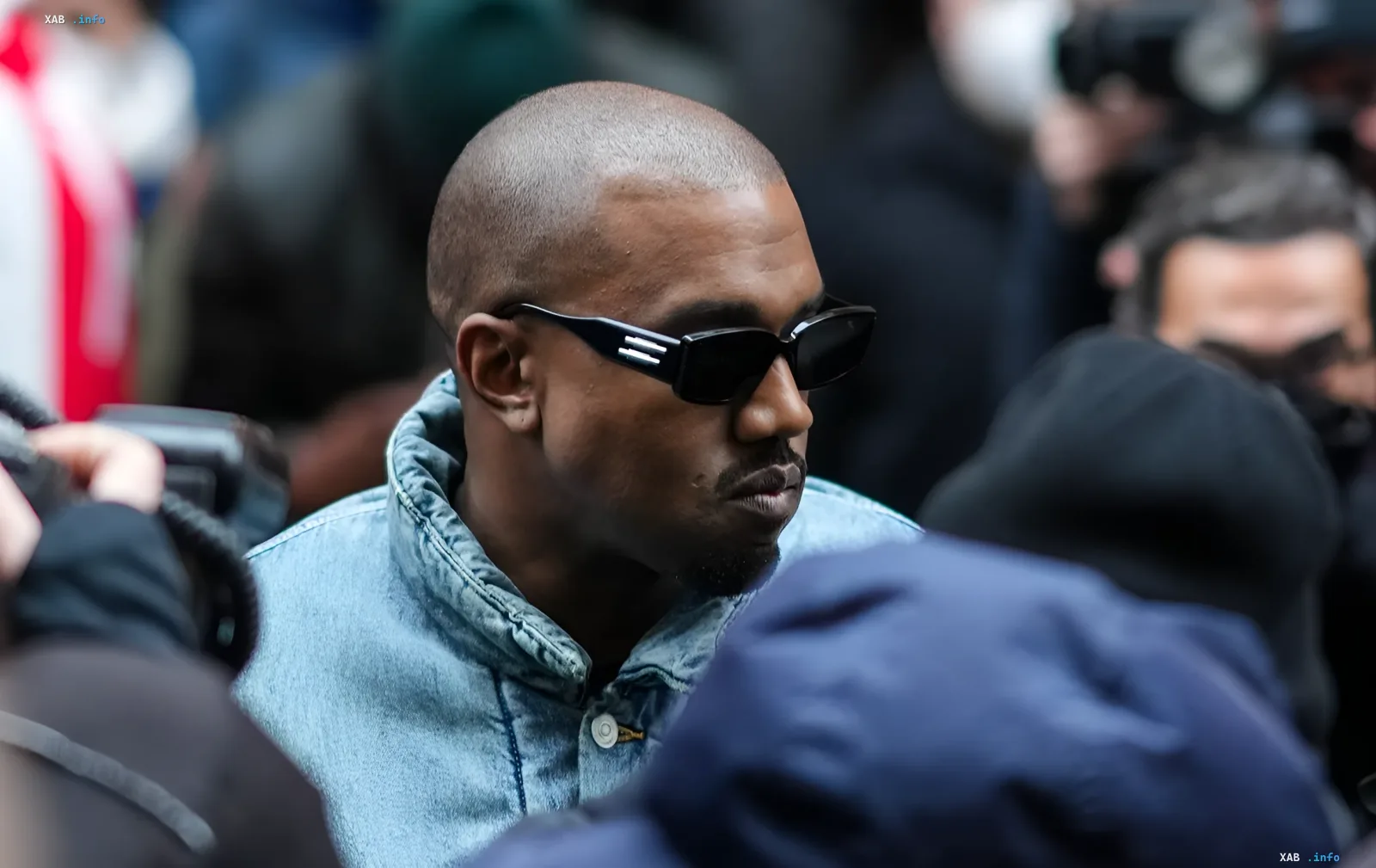 Kanye West in Sonnenbrille und Jeansjacke inmitten einer Menschenmenge, bereitet sich auf seine Rückkehr nach Russland für Konzerte in Sankt Petersburg vor