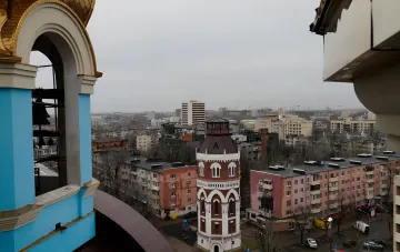 Вид на Мариуполь с колокольни: новые жилые дома и историческая башня на фоне пасмурного неба