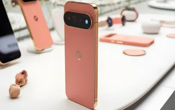 Розовый Google Pixel 11 Pro XL с камерой и логотипом G на белом столе рядом с аксессуарами