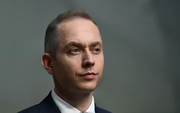 Польский политик Цезарий Томчик в деловом костюме, предупреждающий о возможной провокации в контексте напряженности между Польшей и Россией