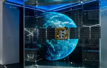 Model of Russian military satellite system 'Rassvet' in a museum with Earth in the background