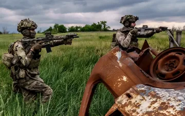 Украинские военные в камуфляже с оружием на фоне ржавого автомобиля в поле, иллюстрирующие оптимизацию военных операций