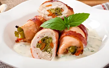Запеченные куриные рулетики с начинкой из перца и сыра, завернутые в бекон, поданные в сливочном соусе с базиликом — пример забытого украинского блюда