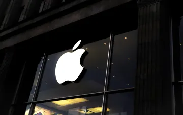 Светящийся логотип Apple на фасаде магазина ночью, символизирующий предупреждение о шпионаже для пользователей из 110 стран