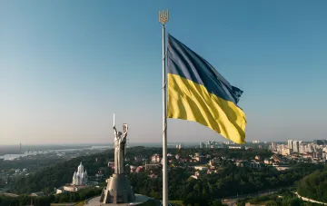 Флаг Украины и памятник Матери-Защитницы на фоне города, символизирующие независимость и празднование Дня Независимости в 2026 году без выходного