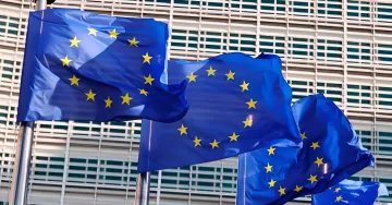 Флаги Европейского Союза на фоне здания Европарламента, символизирующие новые налоговые реформы на табак и вейпы