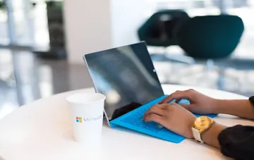 Работа с Microsoft Surface и чашкой с логотипом Microsoft: символ консолидации Copilot