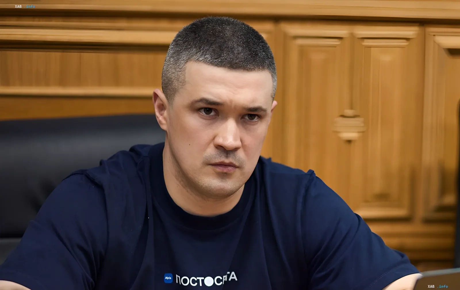 Михаил Федоров в синей футболке с логотипом «ПостСрА» на фоне деревянной панели, обсуждает проведение выборов в условиях войны