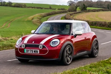 Красный Mini Cooper с белыми полосами на фоне английской сельской дороги — символ нового заднеприводного поколения на платформе BMW Neue Klasse