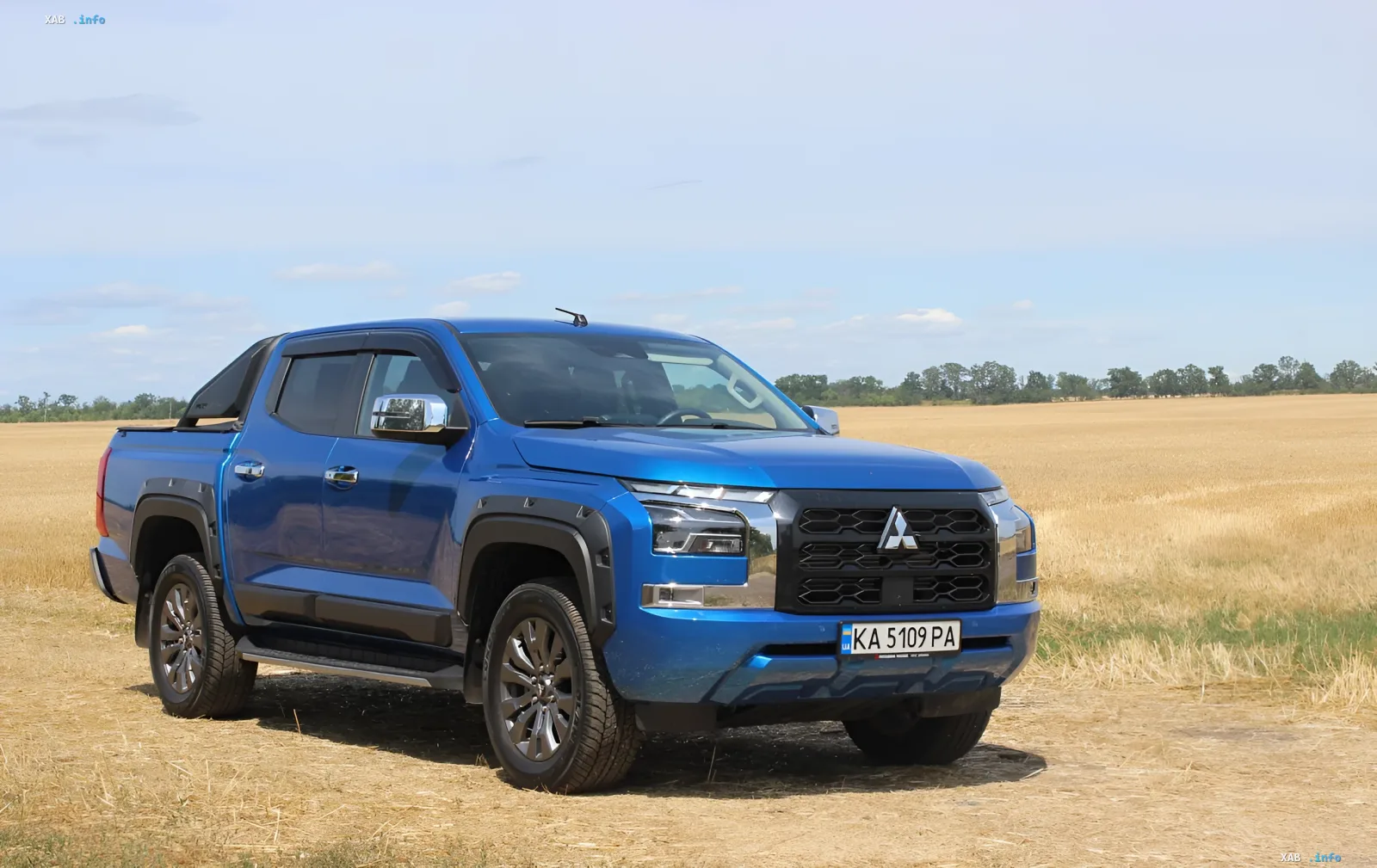 Синий пикап Mitsubishi L200 нового поколения на фоне золотого поля